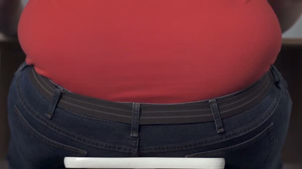 Толстый подросток неуклюже встает со стула, проблемы ожирения в детстве, издевательства — стоковое видео