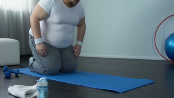 Hombre gordo practicando ejercicio de tablón en la estera durante el entrenamiento en casa, fuerza de voluntad, objetivo — Vídeo de stock