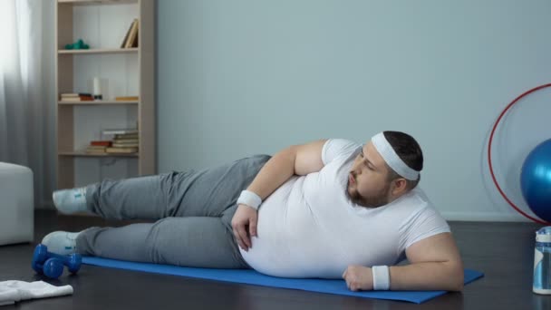 Hombre obeso levantamiento de piernas acostado en la estera, estilo de vida saludable, ocio deportivo, ejercicios — Vídeos de Stock