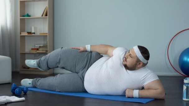 Szorgalmas kövér férfi sportruházat láb gyakorolja otthon, égő kalória — Stock videók