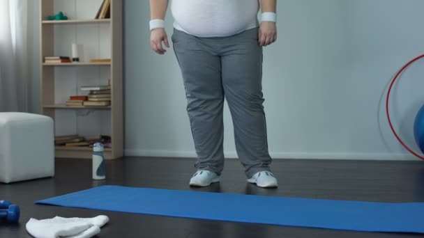 Korpulenter Mann, der auf Matte sitzt, um Sport zu treiben, mühselige Atmung, Fettleibigkeitsprobleme — Stockvideo