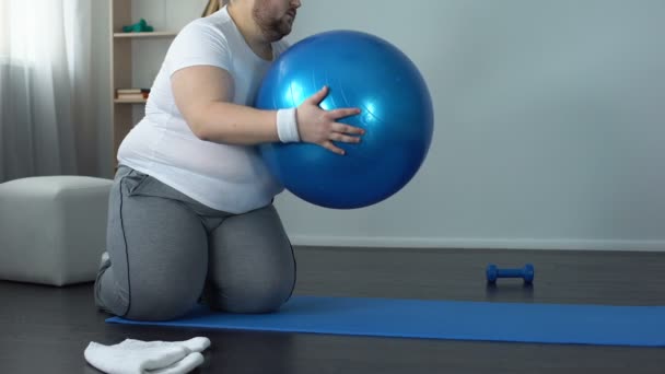 Müder unmotivierter fettleibiger Mann auf Fitnessball liegend, Schlankheitsprogramm