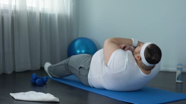 Fettleibige Männer beim Training, Ausdauertraining im Bauch, Sit-ups auf der Matte zu Hause — Stockvideo