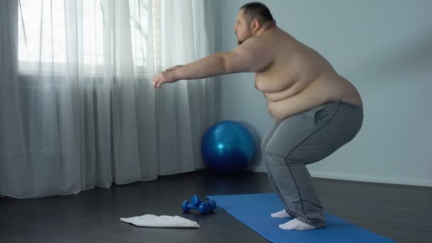 Homme en surpoids faisant des squats à la maison, programme d'entraînement de force des jambes, douleurs articulaires — Video