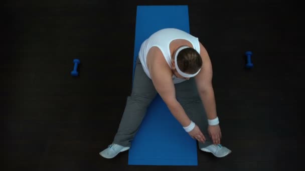 Müder übergewichtiger Mann dehnt sich nach dem Heimtraining auf Matte, Schlankheitsprogramm — Stockvideo