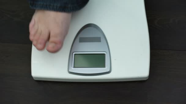 Overweight male feet on weighing scales, measuring kilograms after workout — Stock Video