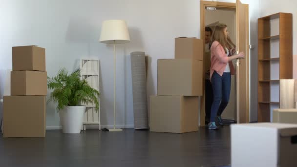 Happy νεαρό ζευγάρι φέρνοντας κουτιά με πράγματα στο διαμέρισμα, μετακίνηση σε καινούριο διαμέρισμα — Αρχείο Βίντεο