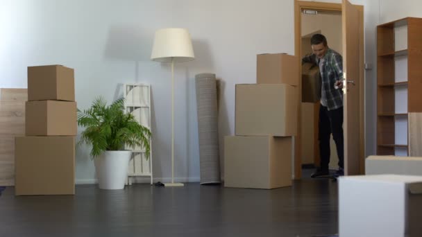 Веселий хлопець приходить з паперовою коробкою до своєї нової орендованої квартири, нерухомості — стокове відео
