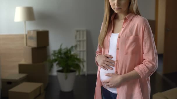 Sorrowful pregnant woman looking at boxes with things, husband leaving family — Stock Video