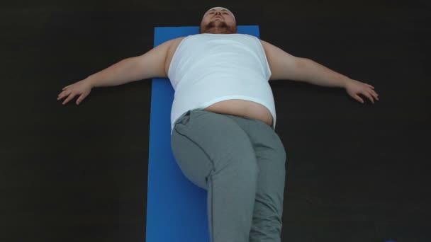 Chubby young man stretching mat after home training top view, healthy activity — Stock Video