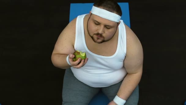Толстяк кусает зеленое яблоко с удовольствием, привычка к здоровому питанию, диета — стоковое видео