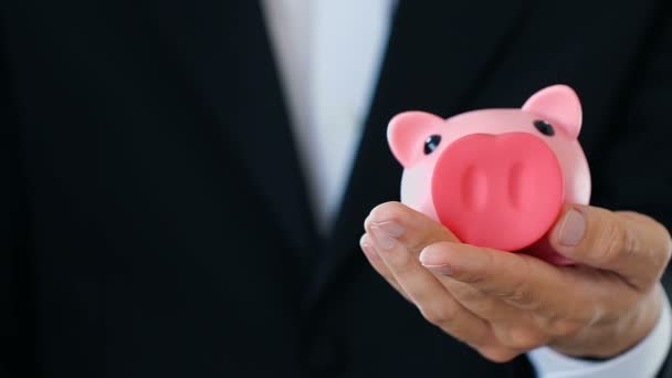 Geschäftsmann legt Geld in Sparschwein, reicher Investor leistet Beitrag — Stockvideo