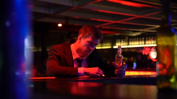 Homem bêbado bebendo uísque de garrafa solitário no pub, caindo no balcão do bar — Vídeo de Stock