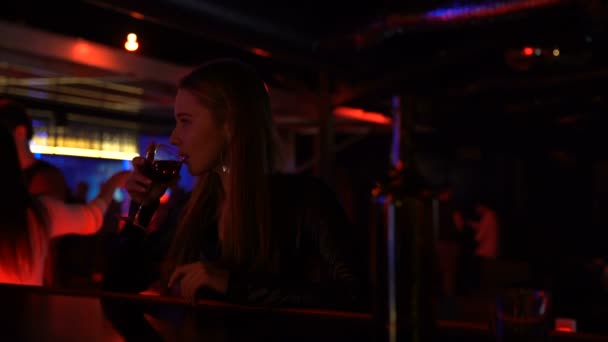 バーのカウンターでワインを飲みながら、解散後知人を探して動揺の女性 — ストック動画