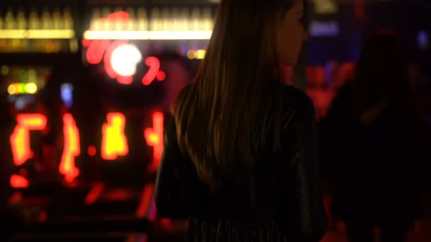 Hermosa mujer de pelo largo esperando a sus amigos en el club nocturno, vista trasera — Vídeos de Stock