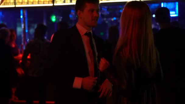 Молодая пара переходит к музыке в диско-клубе, расслабляется на ночной вечеринке вместе — стоковое видео