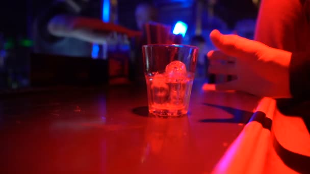 Primer plano de beber alcohol de vidrio masculino en el mostrador de bar en el club nocturno, vida nocturna — Vídeos de Stock
