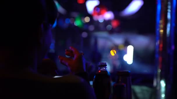 Back view of woman sitting at bar counter and smoking cigarette at night club — Stock Video