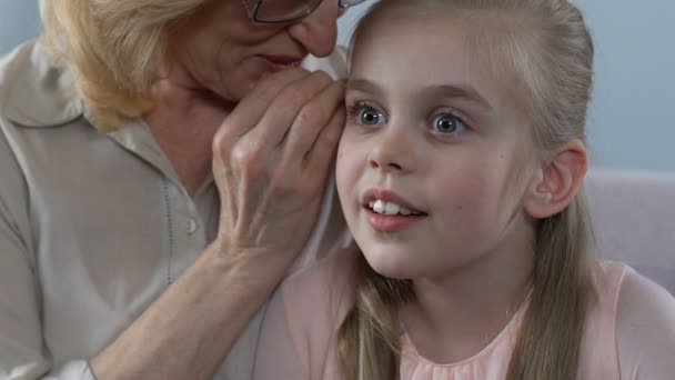 Abuela susurrando secreto a la nieta oído niña sorprendida, familia — Vídeos de Stock