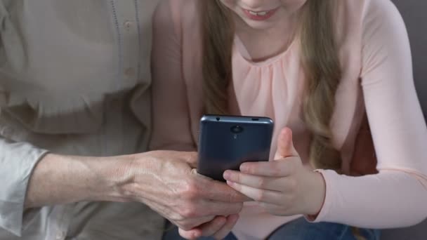 Девочка учит бабушку пользоваться приложением для смартфонов, современными технологиями — стоковое видео