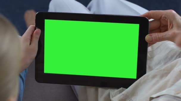 Внучка показывает бабушке мобильные приложения на зеленом экране планшета, курьер — стоковое видео