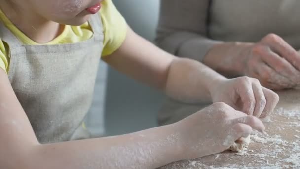 Touching girl carefully helping her grandmother to mold dough, home traditions — Stock Video