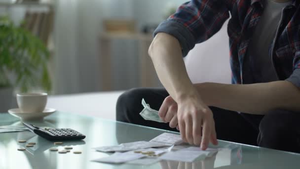 Бідний чоловік обчислює витрати, маючи на столі кілька доларів і центів, борги — стокове відео