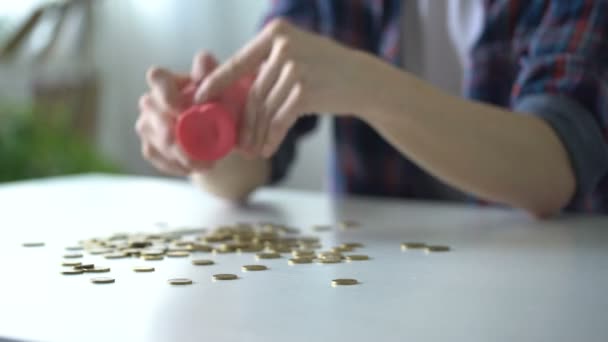 Adolescente derramando moedas do banco porquinho, não há dinheiro suficiente para a compra de sonhos — Vídeo de Stock