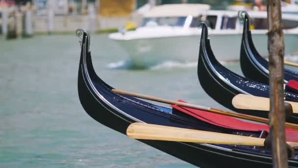 Parkerade gondoler gungande på vatten, vita båten flyter på bakgrunden, Venedig — Stockvideo