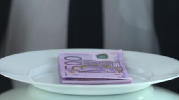 Богатый мужчина ест банкноты с вилкой, понятие потребительского общества, жадный человек — стоковое видео