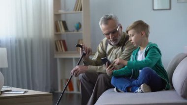 Büyükbaba için cep telefonu, yaşlı adam için basit teknolojileri kullanmayı açıklayan çocuk