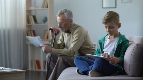 Abuelo leyendo prensa, niño usando tableta, generaciones y el progreso tecnológico — Vídeos de Stock