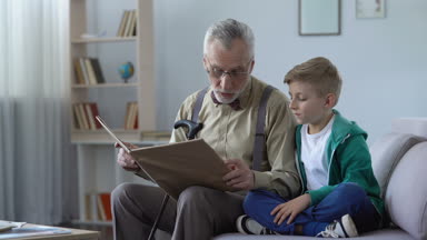Tür yaşlı adam torunu, omuz karşı yaslanmış uysal çocuk için peri masalı okuma