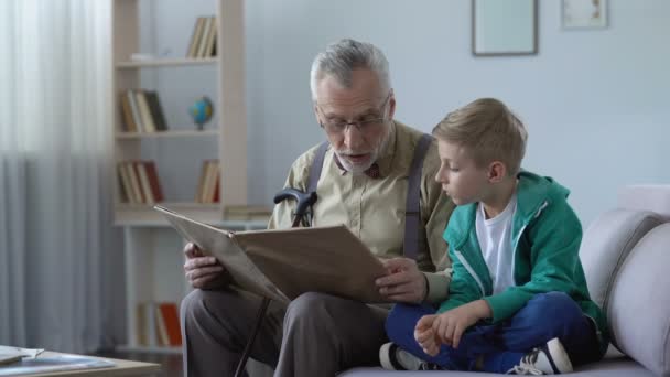 Velho homem lendo livro em voz alta para neto, dando experiência para a geração mais jovem — Vídeo de Stock