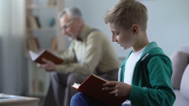 Pequeño chico inteligente leyendo libro, disfrutando de la historia, abuelo orgulloso de nieto — Vídeos de Stock