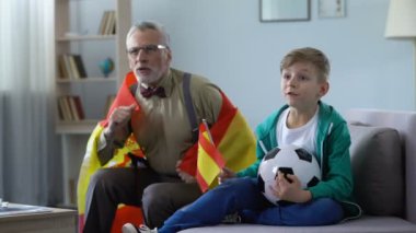 Birlikte evde futbol izlerken torunu ile İspanyol bayrakları sallayarak Büyükbaba