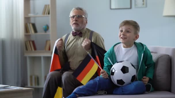 Opa schwenkt mit Enkel deutsche Fahnen, schaut zu Hause Fußball — Stockvideo