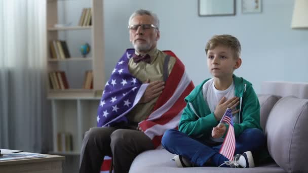 Viejo patriota sosteniendo bandera americana, cantando himno nacional con nieto — Vídeos de Stock