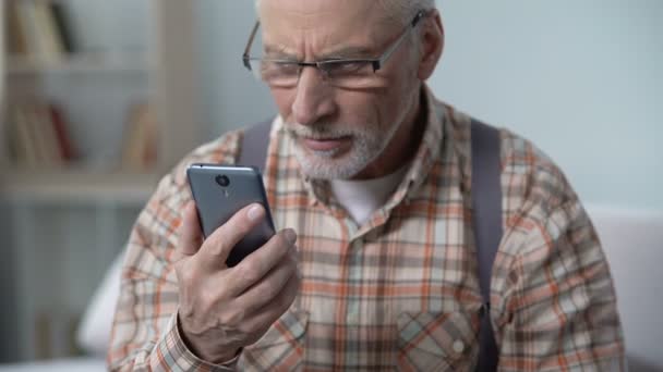Viejo con cautela usando el teléfono inteligente, haciendo bien, software fácil para ancianos — Vídeo de stock