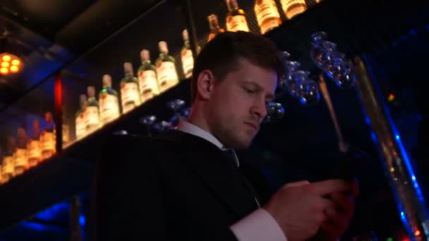 Занят человек в классическом костюме смс с кем-то на смартфоне в ночном клубе, приложение — стоковое видео