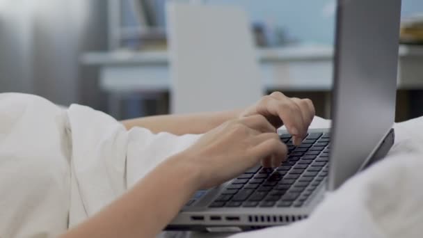 Девушка в наушниках, печатающая на ноутбуке, общающаяся с друзьями в социальной сети — стоковое видео