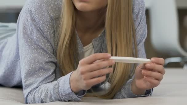 Девушка смотрит тест на беременность, расстроена положительным результатом, боится будущего — стоковое видео