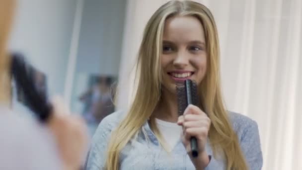 Hübsches Mädchen singt verspielt mit Kamm, unbeschwerte Zeit, Spiegelung im Spiegel — Stockvideo