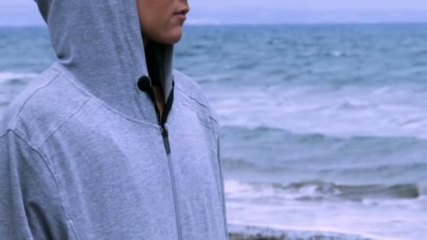 Smutná žena v hoodie kráčel sám na prázdné pláži, při pohledu na obzoru, deprese — Stock video