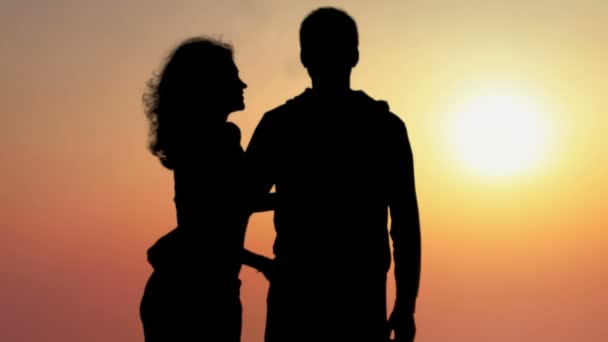 Silhouette of young woman kissing her boyfriend and enjoying beautiful sunset — Stock Video