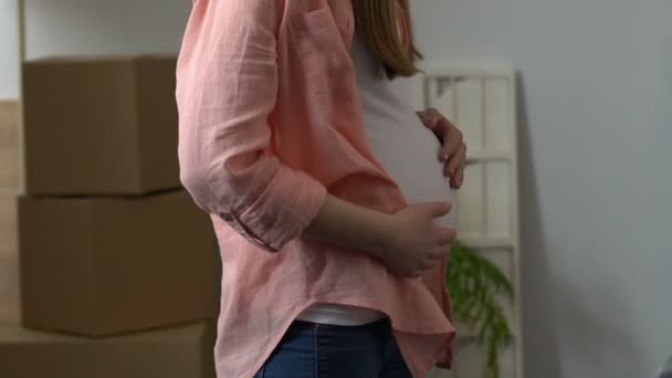 Gravid kvinna kramar hennes make, lycklig ung familj i ny lägenhet, hyra — Stockvideo