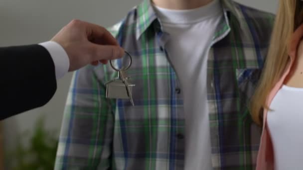 Broker maschile dando le chiavi per felice giovane famiglia acquisto di proprietà, acquisto congiunto — Video Stock