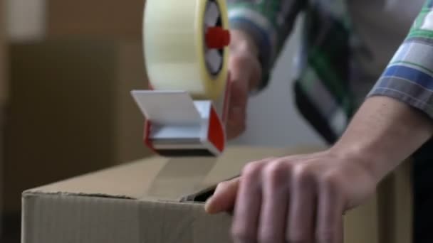 Uomo imballaggio scatola di cartone con nastro adesivo, trasferirsi fuori, migrazione, cambiamento di vita — Video Stock