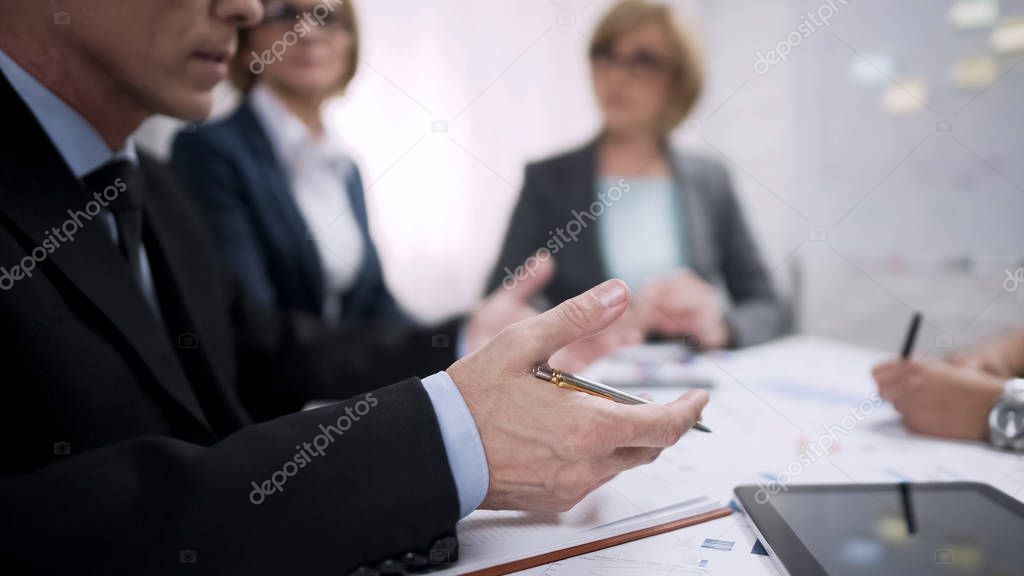 Male boss giving instructions to managers concerning their reports, meeting