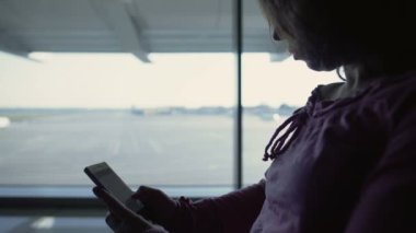 Kadın turist online kitap okuma harcamak zaman havaalanında uçuş için bekliyor